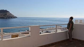 A balcony with a view of the sea and a rocky island.