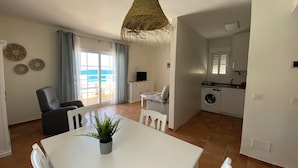 A modern apartment with a dining area, kitchen, and a balcony with a view of the sea. - Aparthotel Vistamar (Nijar)