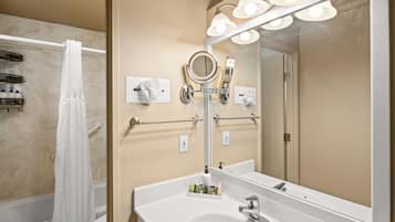 A bathroom with a white sink, a mirror with lights, a towel rack, and a shower curtain.