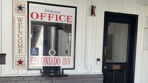 A welcome sign for the Escondido Inn office, a black door, and a brick wall. - Escondido Inn (Escondido)