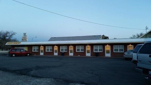 A motel with a row of single-story rooms, a parking lot, and a visible sign for the motel.