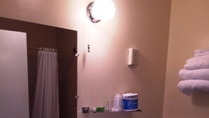 A bathroom with a white sink, mirror, toilet, and a shelf with toiletries. - Sharon Motel (Wells)