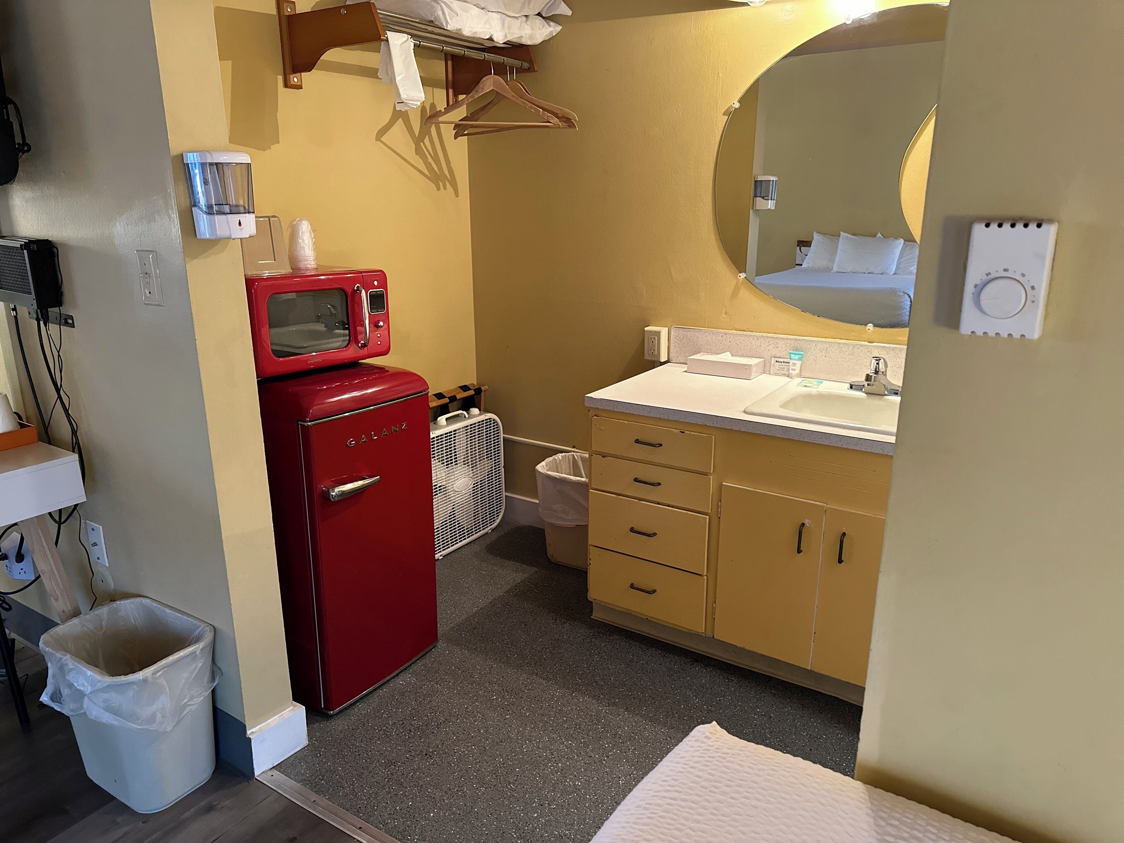 Een kleine badkamer met een rode magnetron, een wastafel en een spiegel.