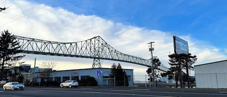 A bridge over a road with cars, a building, and a billboard.