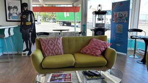 A lobby with a green sofa, a glass coffee table, and a Batman statue.