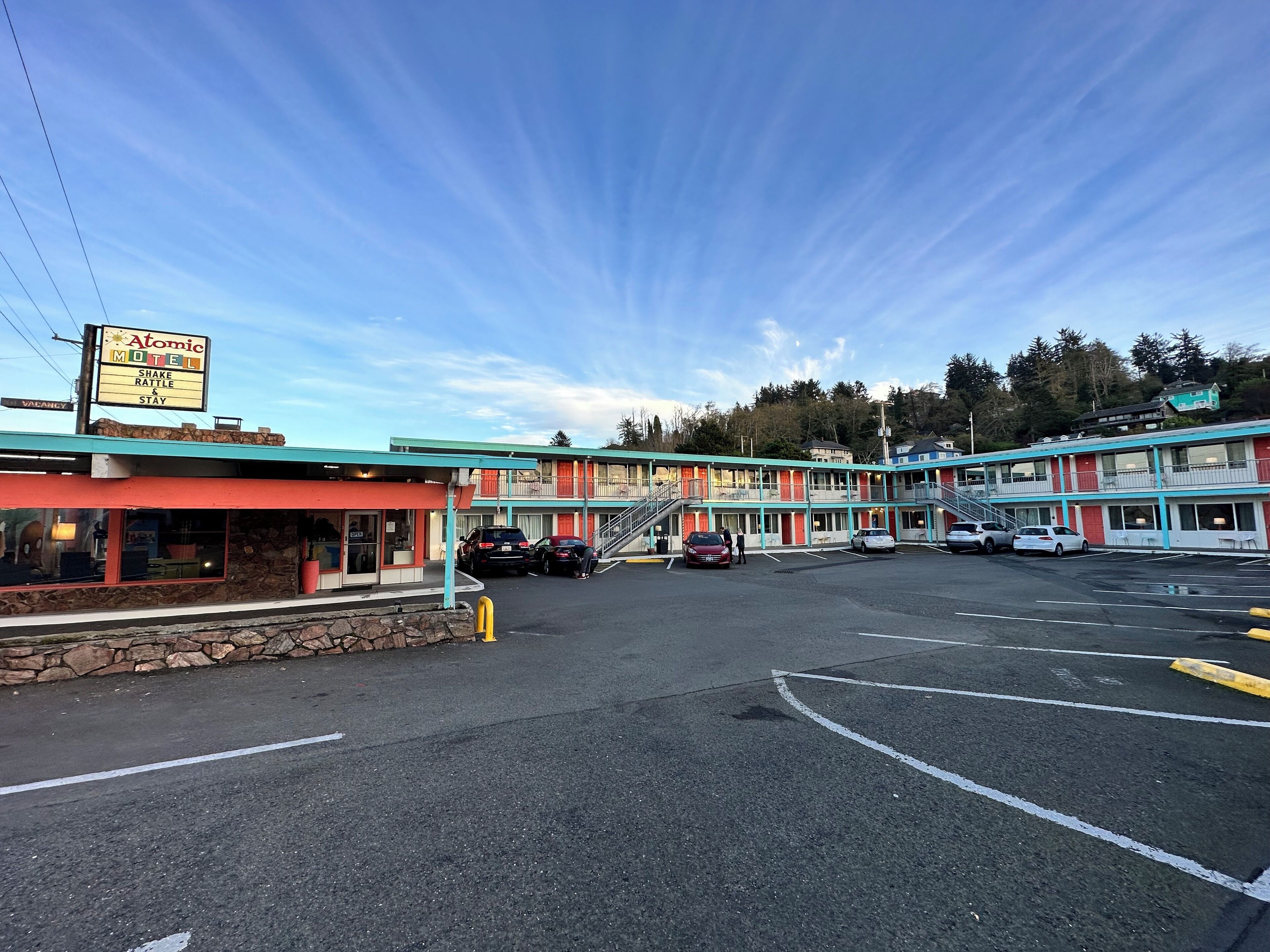A motel with a signboard, multiple parking spaces, and a clear sky.