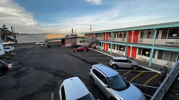 Een motel met een tweelaags gebouw, meerdere parkeerplaatsen en een heldere lucht.