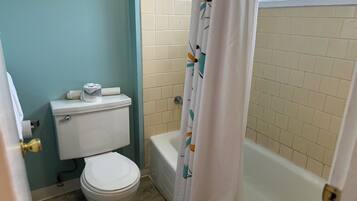 Un baño con inodoro, bañera y cortina de ducha.
