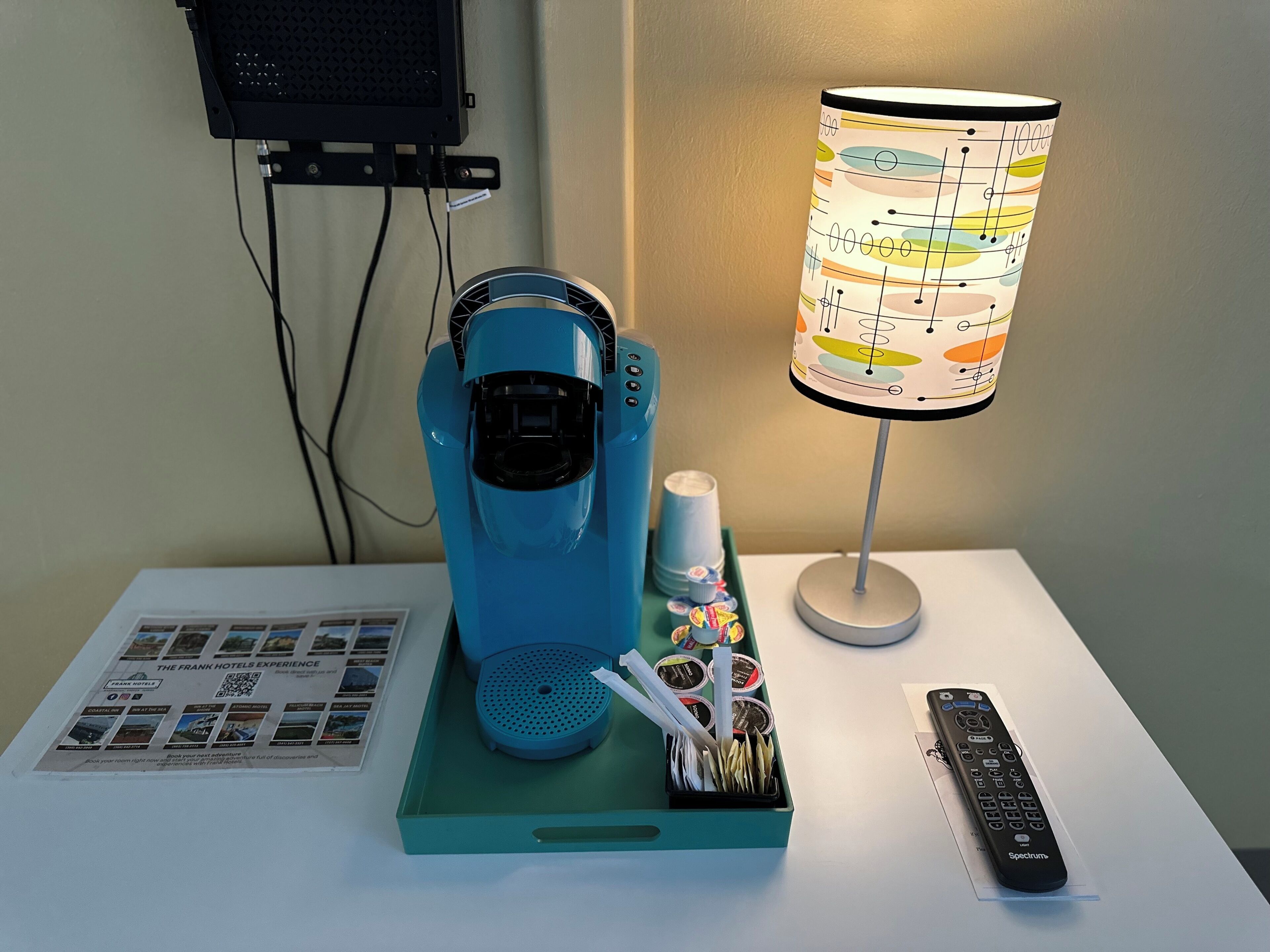 Eine Kaffeemaschine, eine Lampe und eine Fernbedienung stehen auf einem Tisch.