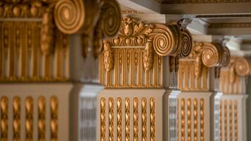 Colunas douradas ornamentadas com desenhos intrincados e estilo arquitetônico clássico.