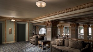 Ein geräumiges Wohnzimmer mit einem gemusterten Teppich, zwei Sofas, einem Couchtisch und aufwendigen Deckenverzierungen.