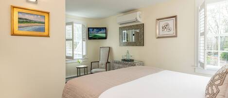 A hotel room with a bed, a television, a mirror, and a window.