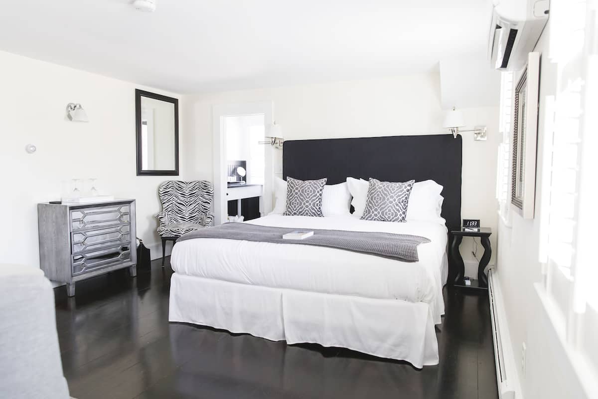 Un dormitorio moderno con una cama grande, un tocador, una silla y un espejo.