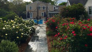 Ein Wohnhaus mit geschlossenem Eingang, einem Swimmingpool und einem Garten mit blühenden Pflanzen.
