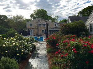 Ein Wohnhaus mit geschlossenem Eingang, einem Swimmingpool und einem Garten mit blühenden Pflanzen.