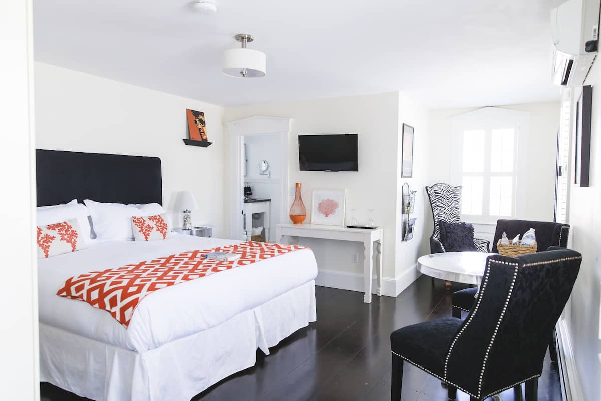 Habitación de hotel con una cama grande, un escritorio, una silla, un televisor y una ventana.