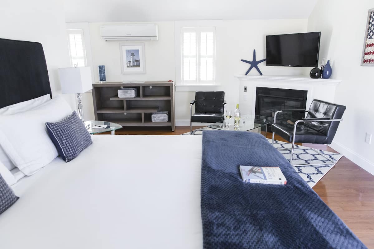 Una habitación de hotel moderna con una cama grande, un televisor de pantalla plana, una chimenea y una decoración con forma de estrella de mar.
