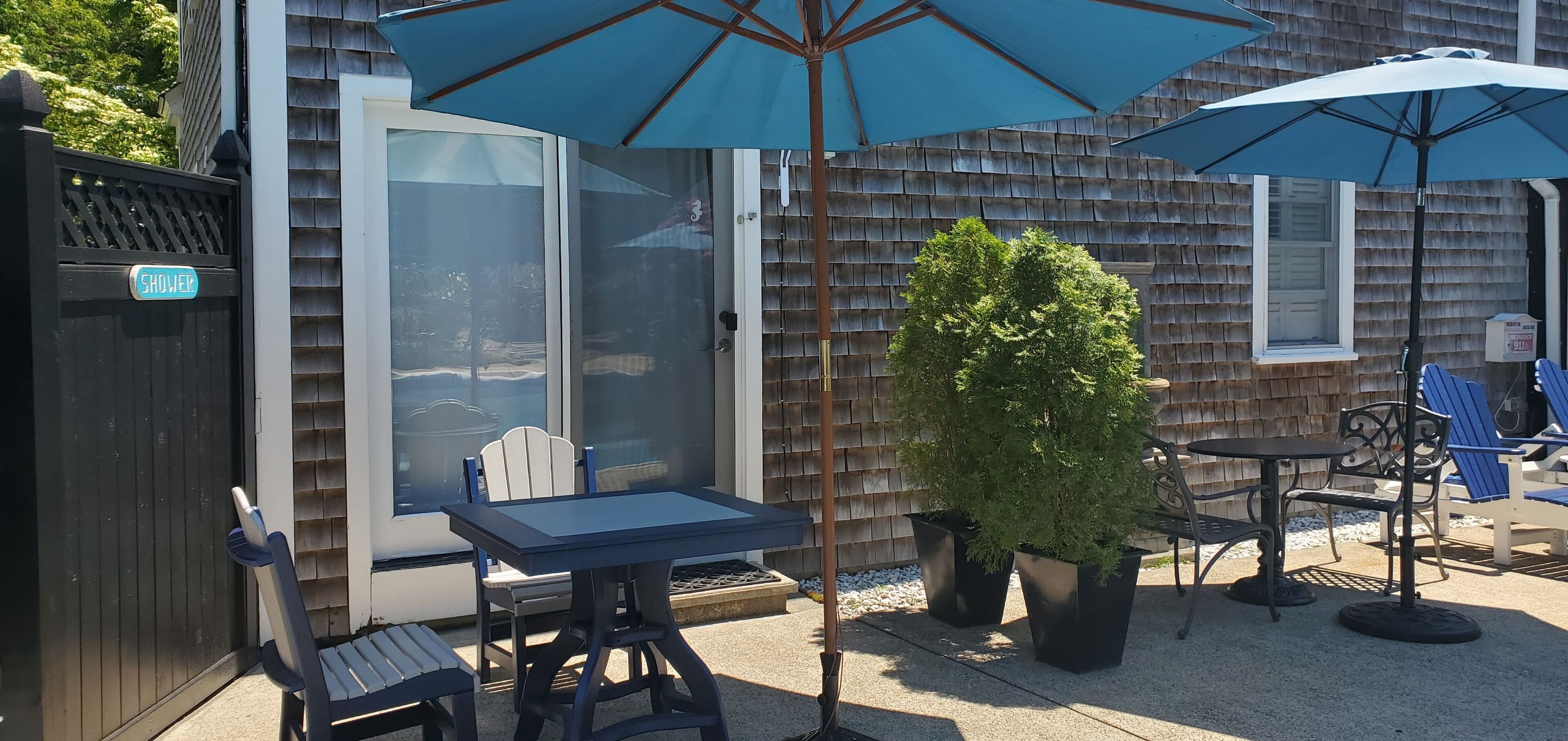 A patio area with a table and chairs, two umbrellas, and a potted plant.