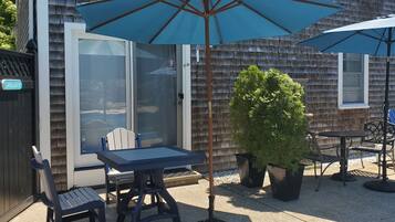 A patio area with a table and chairs, two umbrellas, and a potted plant.
