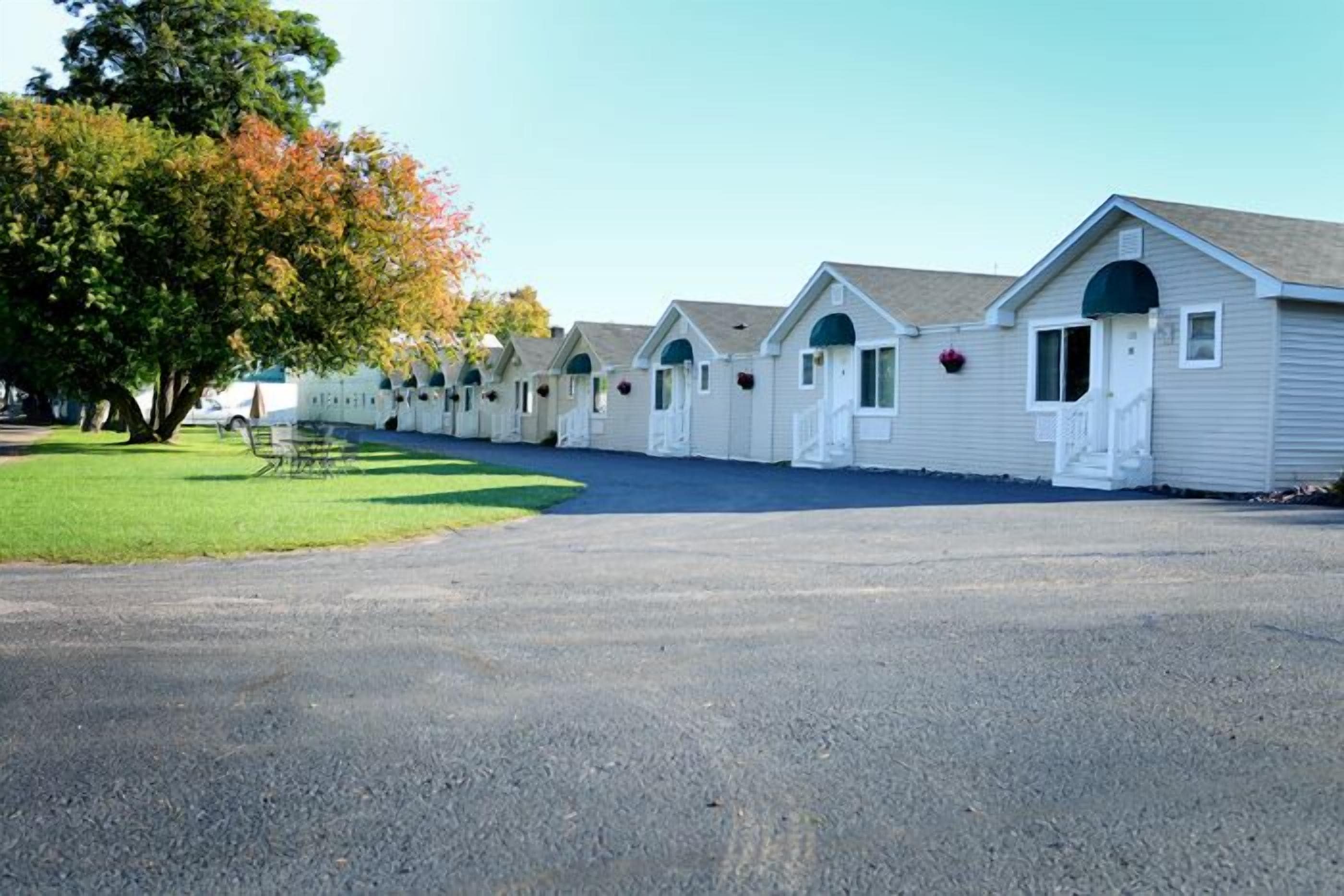 Une rangée de maisons mobiles de plain-pied, chacune dotée d’un porche individuel, disposées en ligne droite le long d’une allée pavée.