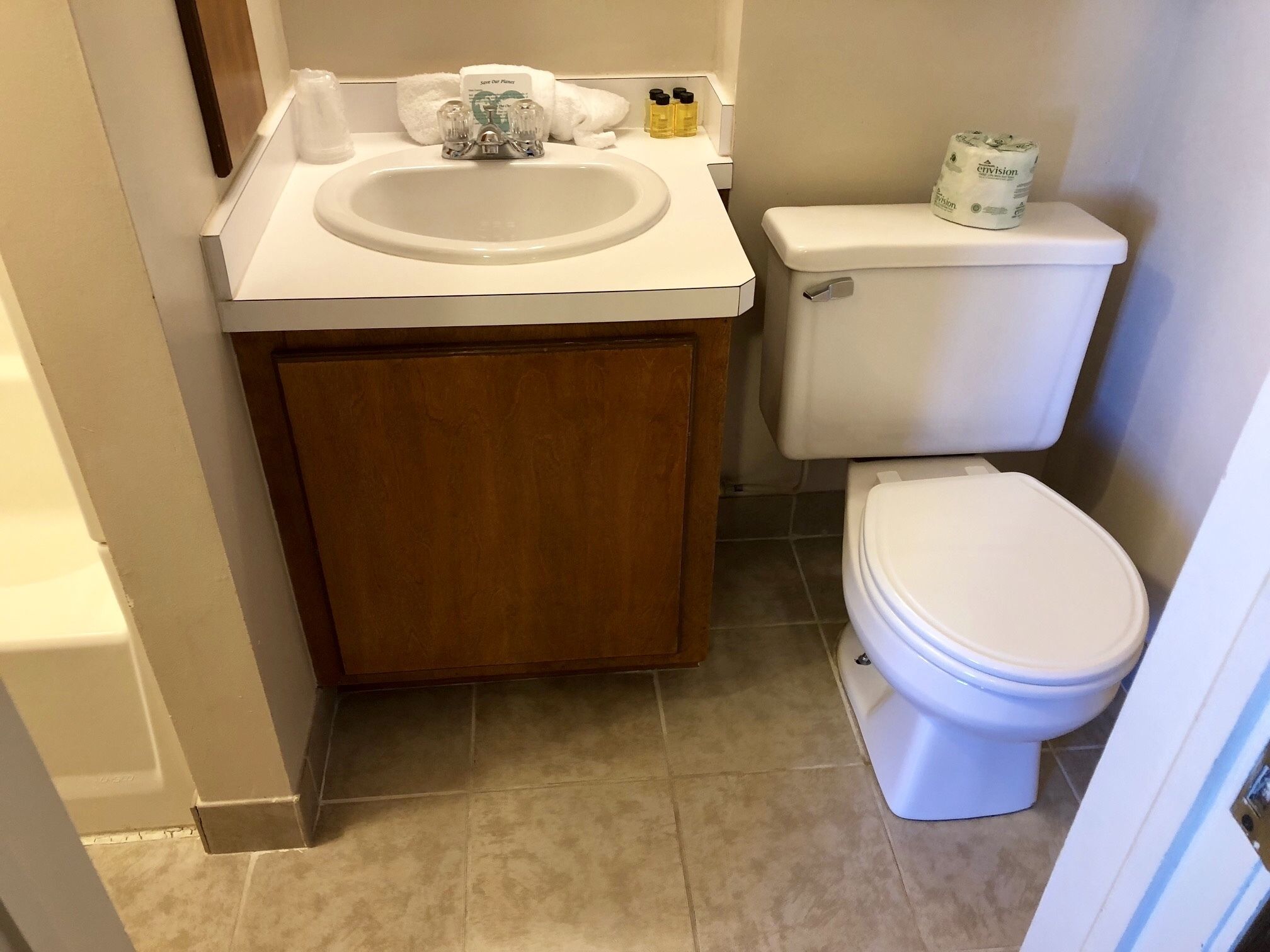 Une salle de bain avec un lavabo blanc, un meuble en bois et des toilettes blanches.