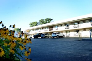 Ein Motel mit Parkplatz, mehreren parkenden Autos und einem Gebäude mit mehreren Balkonen.