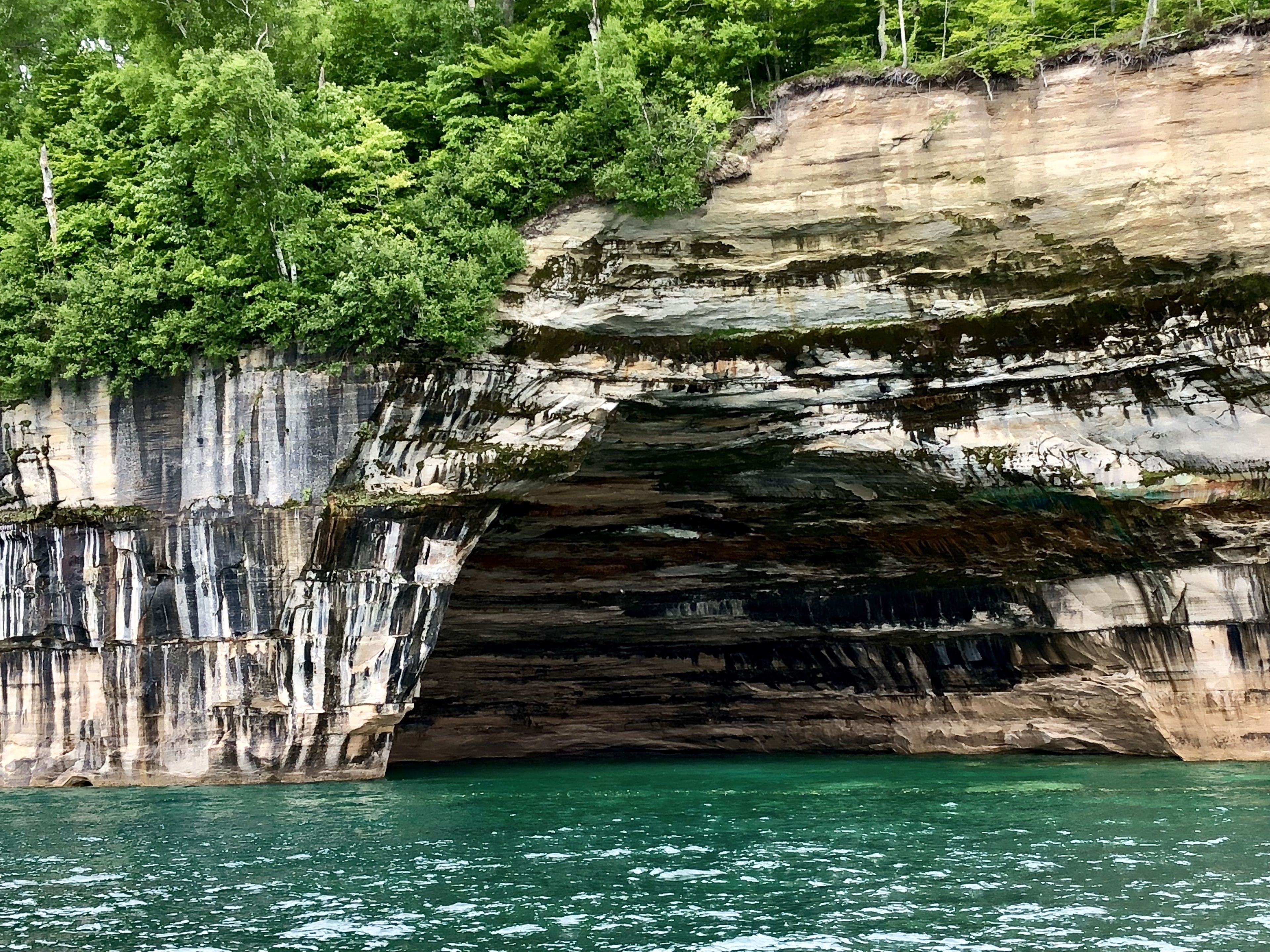 A natural rock formation with a water body below.