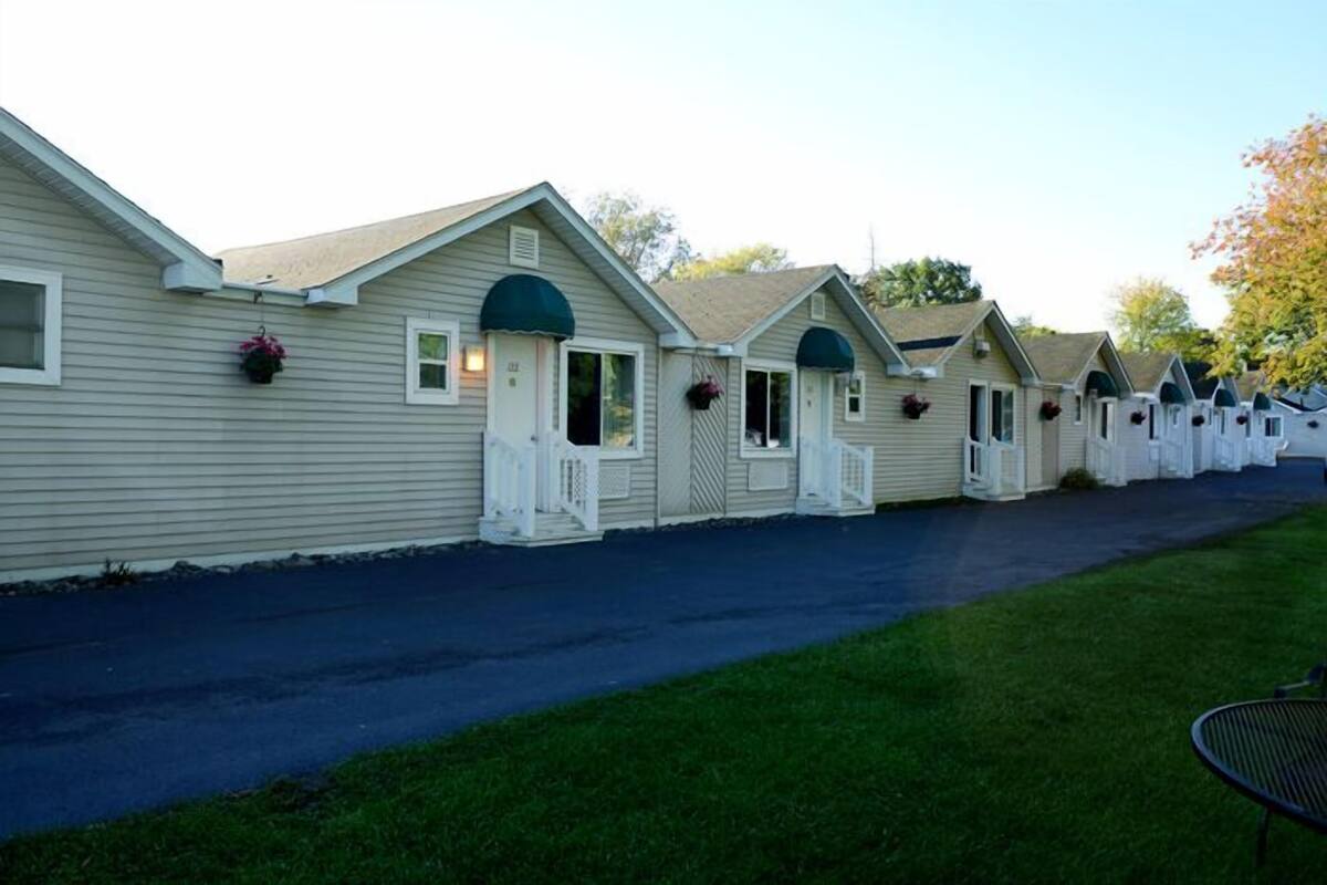 A row of single-story cabins with individual porches and flower boxes, connected by a shared driveway.