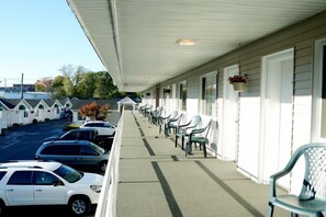 Ein Motel mit überdachter Veranda, mehreren Reihen aus Plastikstühlen und einem Parkplatz mit Autos.