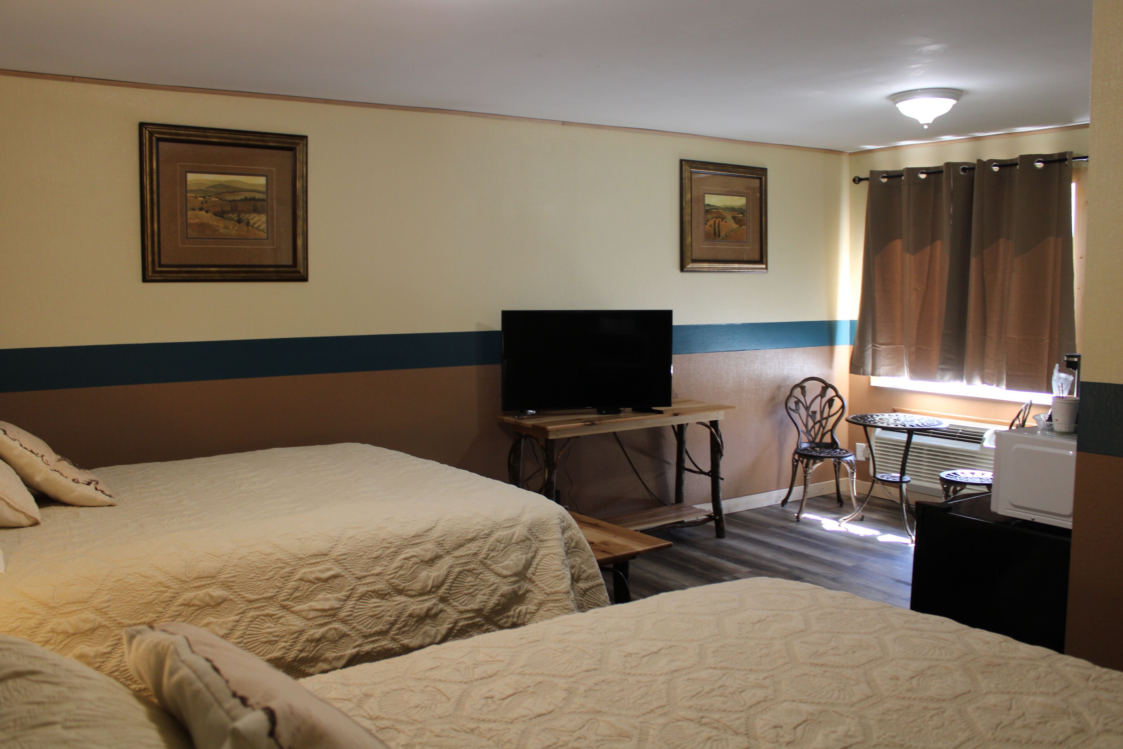 Een hotelkamer met twee bedden, een televisie, een tafeltje en een stoel.