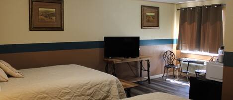 Een hotelkamer met twee bedden, een televisie, een tafeltje en een stoel.