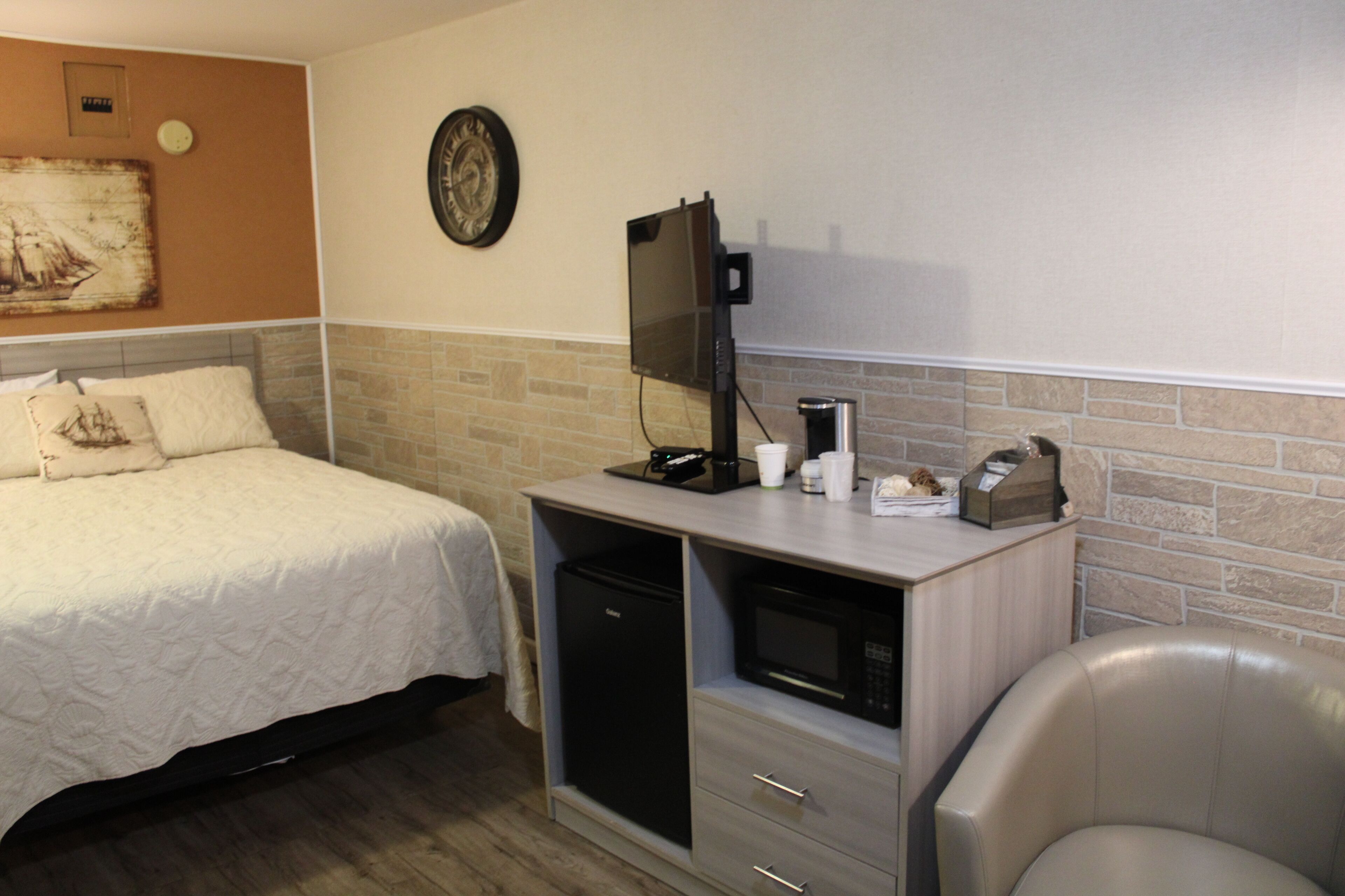 A hotel room with a bed, a desk with a computer, a microwave, and a coffee maker.