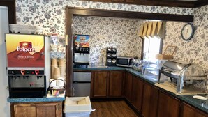 Uma cozinha com um sistema de café Folgers Select Brew, micro-ondas, torradeira e pia.