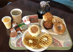 Ein Frühstückswagen mit Waffeln, Beuteln, Muffins, Kaffee und verschiedenen Frühstücksgetränken.
