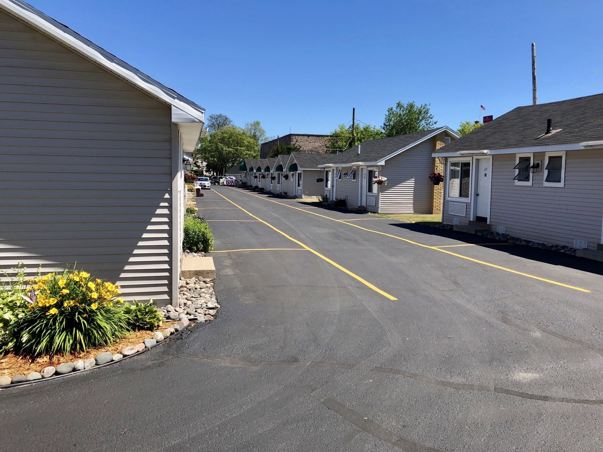 A row of single-story mobile homes with a paved driveway and yellow parking lines.