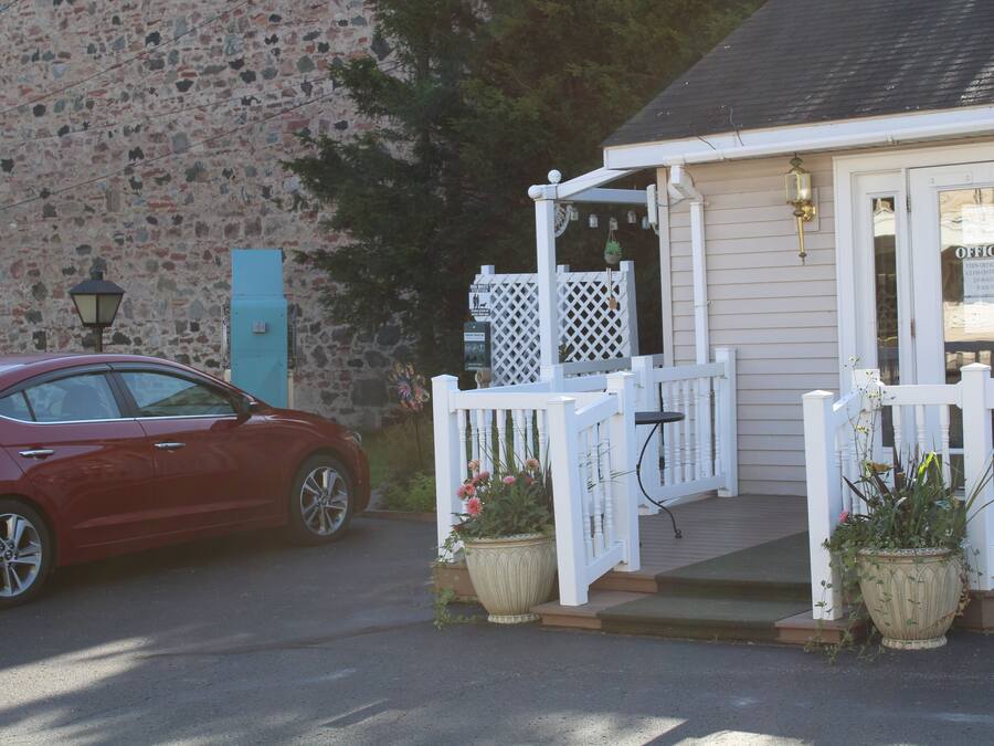 A red car parked in front of a building with a white porch and a sign that reads "OFFICE".