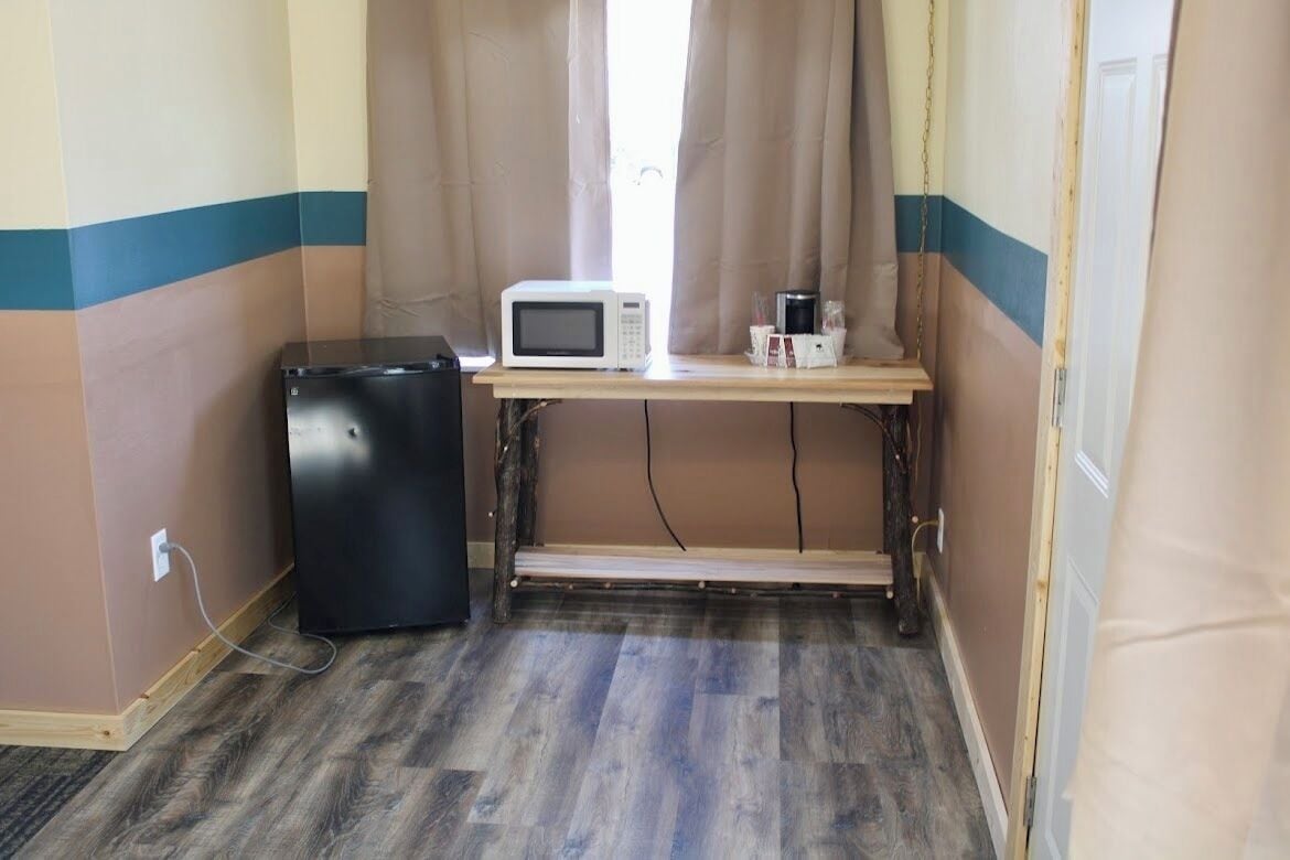 A compact kitchenette with a microwave, a small refrigerator, and a wooden table.