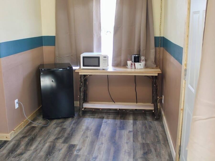 A compact kitchenette with a microwave, a small refrigerator, and a wooden table.