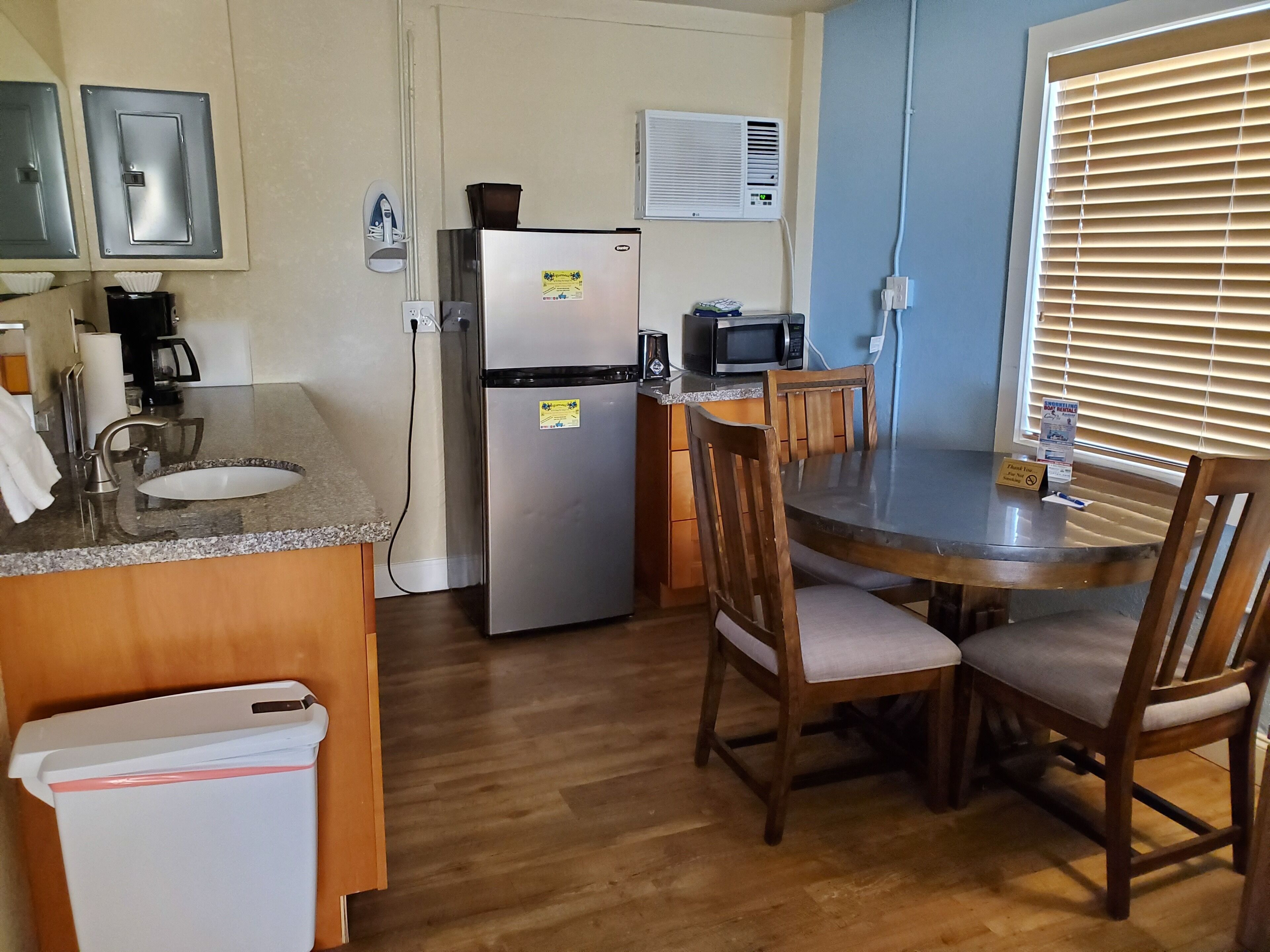 A compact kitchen with a sink, refrigerator, microwave, and a dining table with chairs.