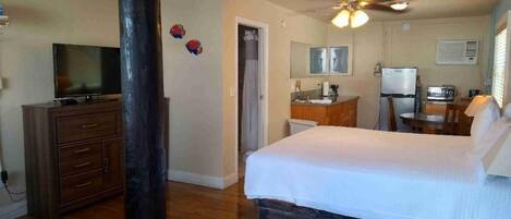 A hotel room with a bed, a desk, a television, a wardrobe, and a bathroom.
