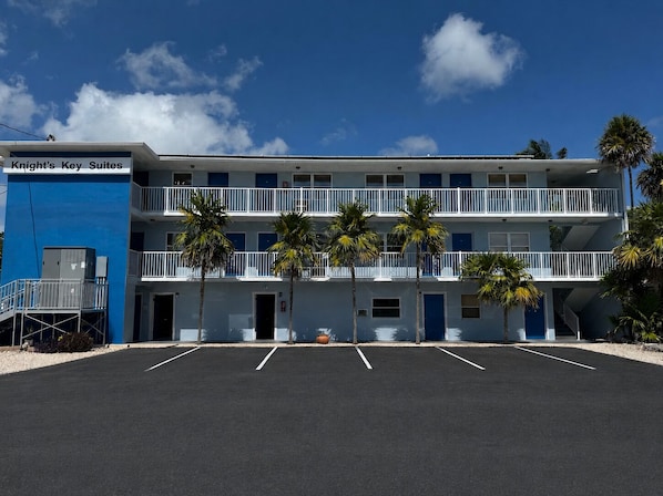 A motel with a blue exterior, multiple balconies, and a parking lot.