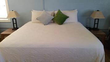 A neatly made bed with a white duvet, two bedside lamps, and a green pillow.