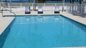 Een buitenzwembad, ligstoelen bij het zwembad