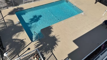 A rectangular swimming pool with a metal ladder and a safety sign.