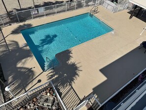 A rectangular swimming pool with a metal ladder and a safety sign.