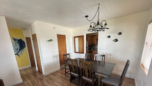 A dining area with a wooden table and chairs, a chandelier, and a kitchen in the background. - Knight's Key Suites (Marathon)