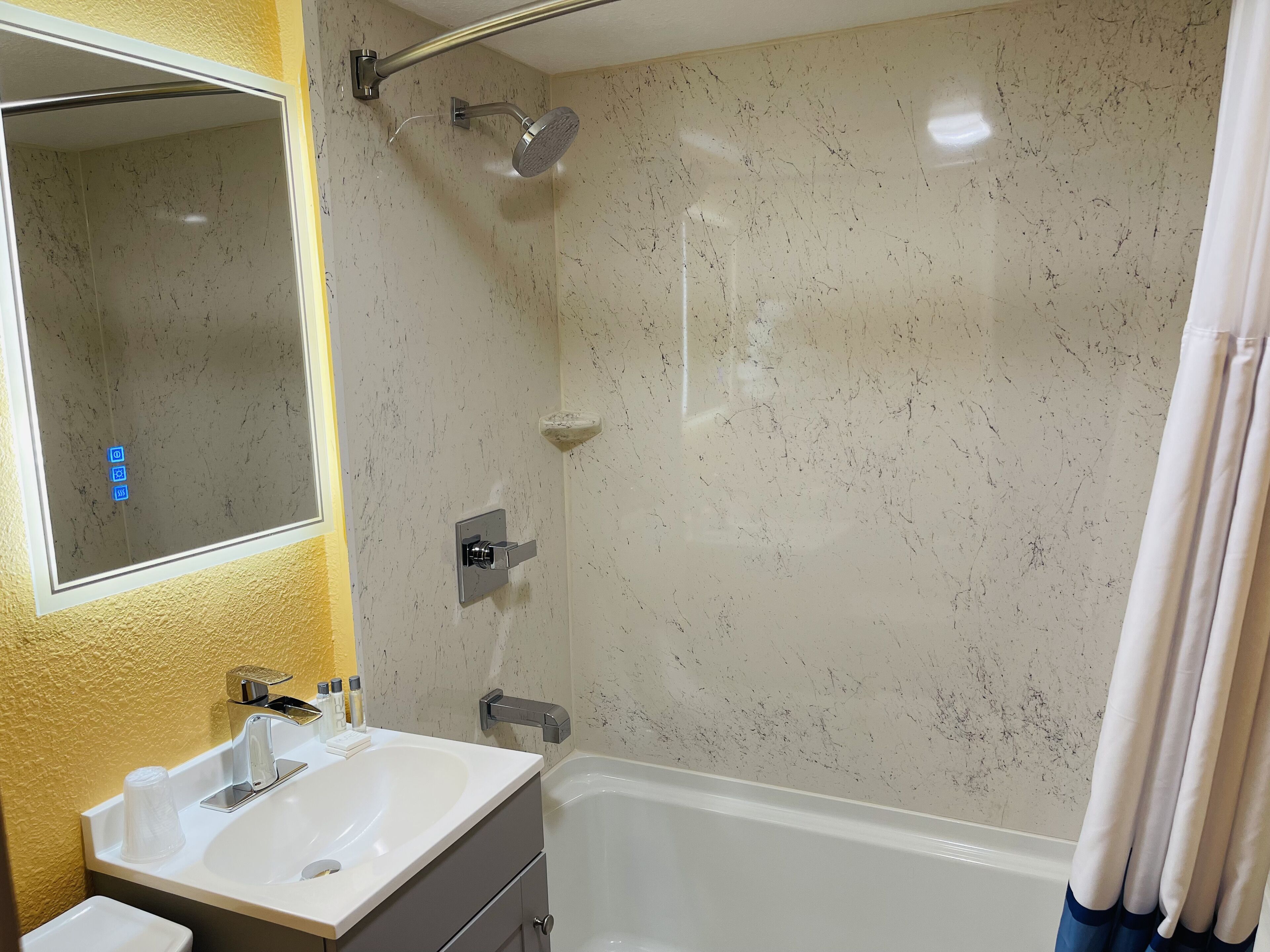 Un baño con lavamanos, espejo, ducha y bañera.