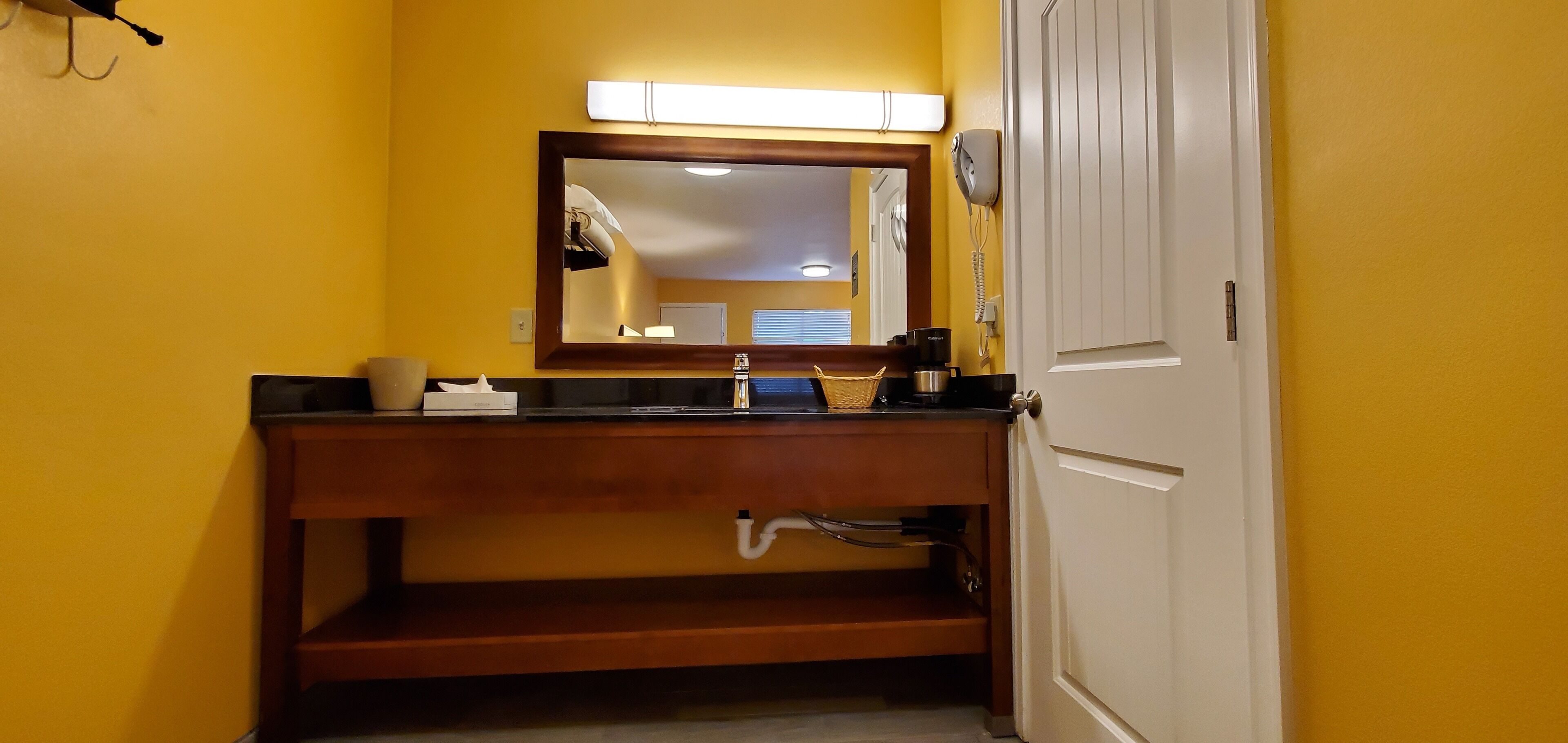 Ein Badezimmer mit einem Holzkosmetikschrank, einem Spiegel, einem Waschbecken und einer Toilette.