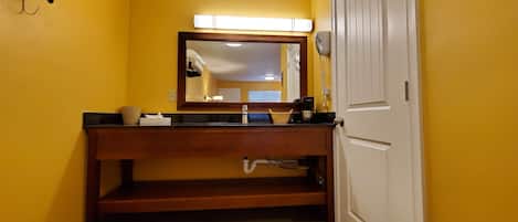 Ein Badezimmer mit einem Holzkosmetikschrank, einem Spiegel, einem Waschbecken und einer Toilette.