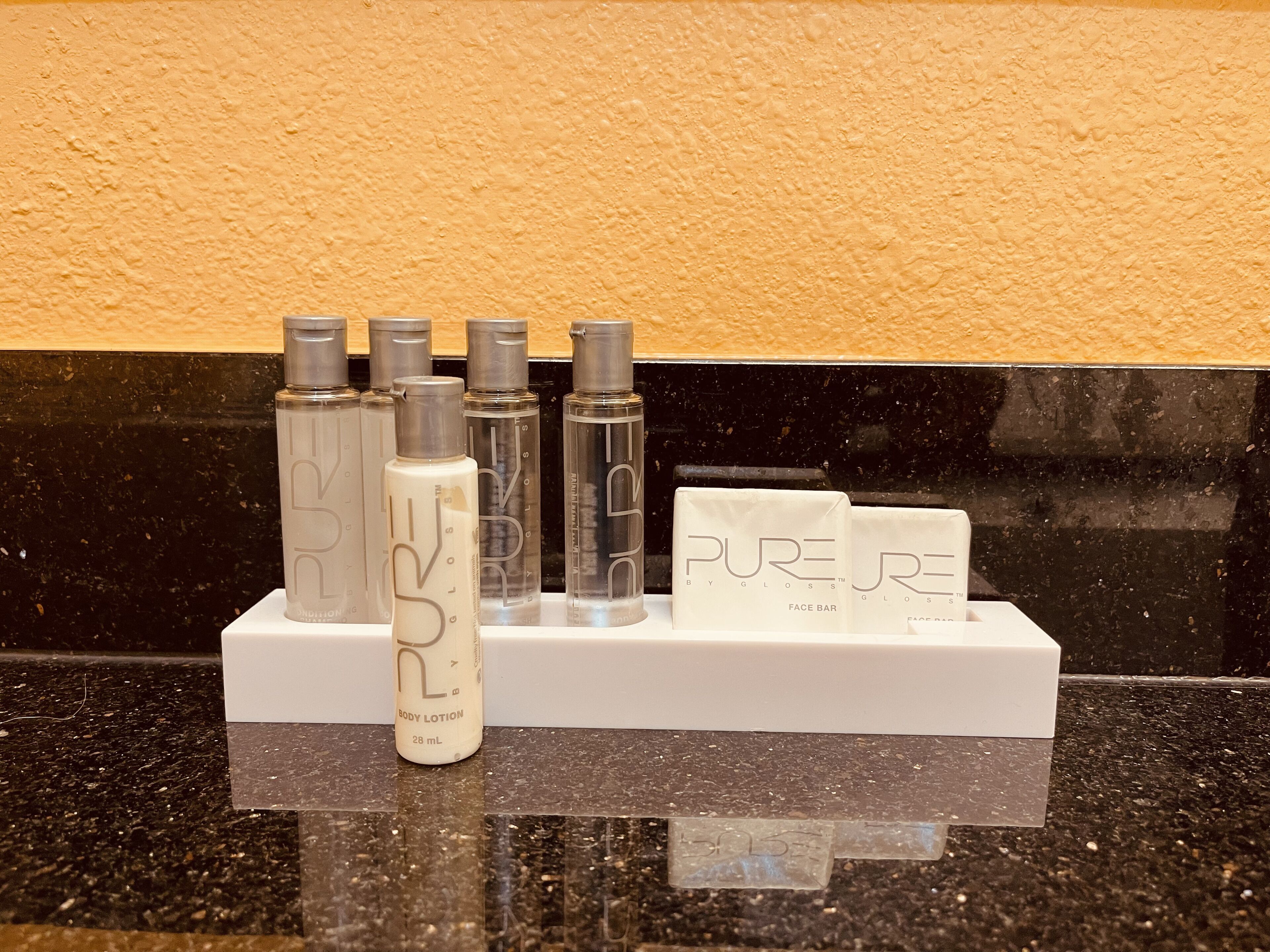 A display of Pure by Gloss™ body lotion and face bar products on a countertop.